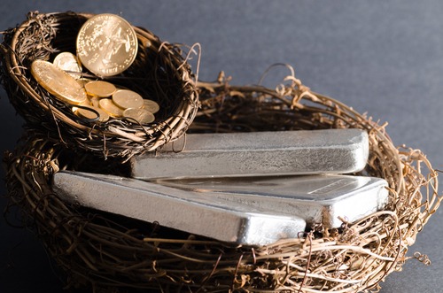 Gold and silver bars nestled in a bird's nest, symbolizing the safe and secure investment in precious metals.